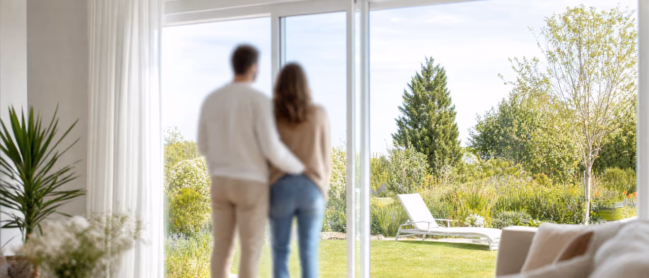 Couple de dos regardant le jardin depuis un intérieur chaleureux